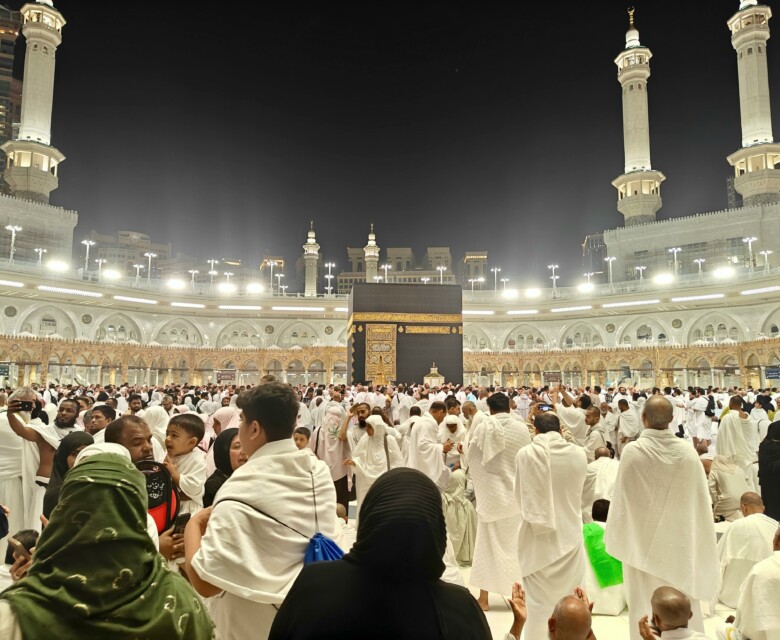 Night view of pilgrims gathered around the Kaaba in Mecca, Saudi Arabia during Hajj.