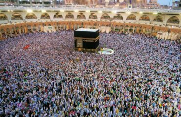 Aerial view of a large crowd of pilgrims gathered around the Kaaba in Mecca for religious rituals.